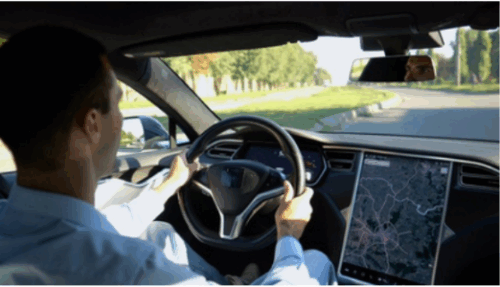 Photo taken from the back seat of an EV showing a man driving the car