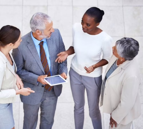 Photo, taken from above, of 4 business people having a stand-up discussion.